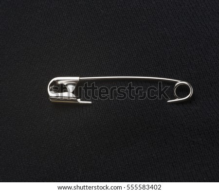 safety pin on black fabric Royalty-Free Stock Photo #555583402