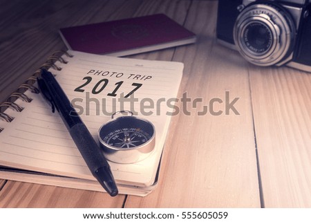 Top view of PHOTO TRIP 2017 written on the notebook,travel planning concept.note book,compass,passport,film camera on the wooden desk.