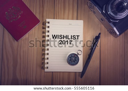Top view of WISH LIST 2017 written on the notebook,travel planning concept.note book,compass,passport,film camera on the wooden desk.