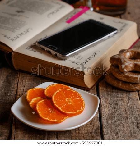 slices of tangerine on the table, a book and a cell phone

