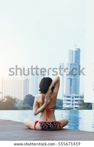 Woman in bikini relaxing with Yoga exercises at the swimming pool.