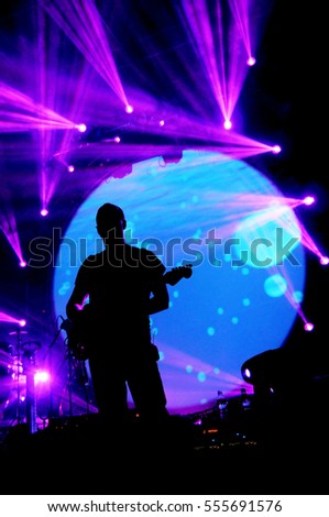 Guitarist on stage with colorful lightshow Royalty-Free Stock Photo #555691576