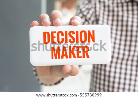 Man hand showing DECISION MAKER word phone with  blur business man wearing plaid shirt.