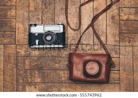 Film camera and cover him lie on the wooden background.