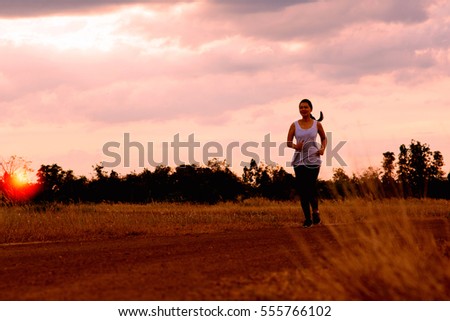 Young sporty girl running on a rural road . At the sunset.