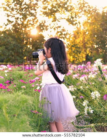 Women holding a camera. Photography in the flower garden.