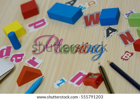 Collection of motivation words "planning" over stationery and wooden background