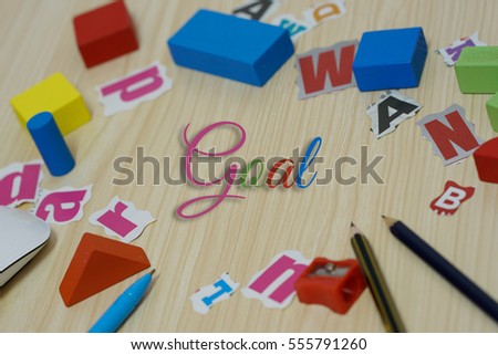 Collection of motivation words "goal" over stationery and wooden background