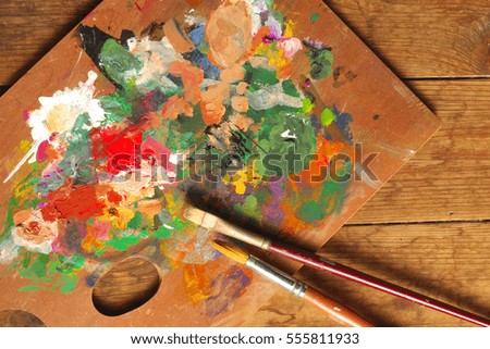 Palette and paintbrushes on wood background