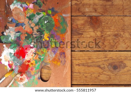Palette and paintbrushes on wood background