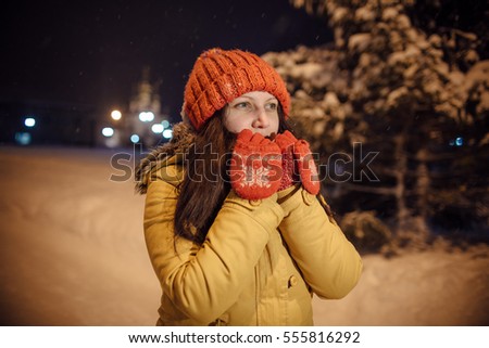 the girl's portrait against the background of the evening city which has frozen and warms in the winter hands. in the light of city lamps.