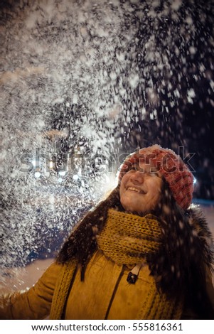 the girl's portrait in the winter who throws up snow. contrast in the light of city lamps. emotions