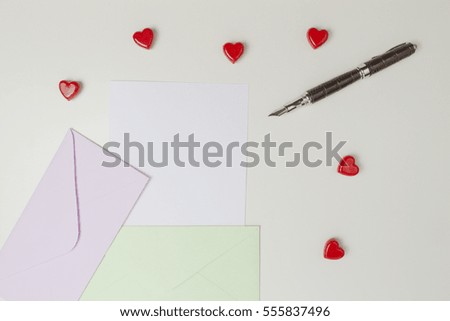 Envelopes, message, pen and small red hearts on white table. Love letter, valentines day concept