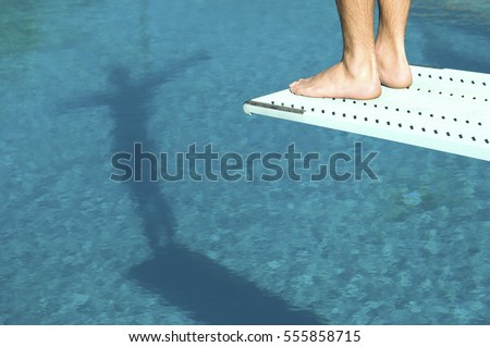 Male swimmer standing on diving board Royalty-Free Stock Photo #555858715