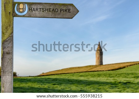 Arrow showing the direction of Hartshead Pike which is a hill in Tameside in Greater Manchester, England, and its name is associated with the monument on its summit.
