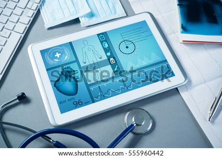 White tablet pc and doctor tools on gray surface Royalty-Free Stock Photo #555960442