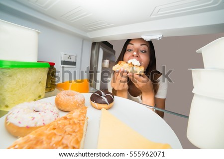Young Woman Eating Slice Of Sweet Cake In Refrigerator Royalty-Free Stock Photo #555962071