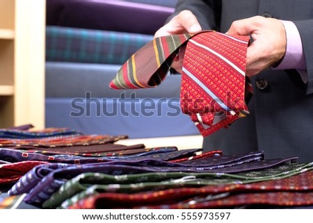 Closeup midsection of a businessman selecting ties in clothes store Royalty-Free Stock Photo #555973597