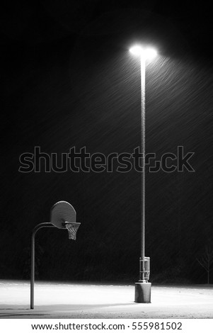 Basketball hoop at night in the snow-Vertical. 