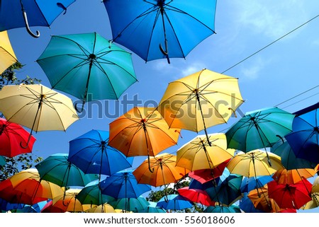 Colorful umbrella hanging from the outdoor top sling on blue sky day in the park