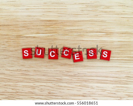 word success, white alphabet on tiny red magnet plates on wooden table floor, flat lay close-up top view with copy space
