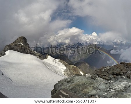 View of rainbow shining beside Mount Robie Reid summit and north face glacier from lower on summit ridge, Garibaldi Ranges, Mission, British Columbia, Canada Royalty-Free Stock Photo #556071337
