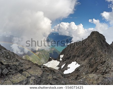 Rainbow over north face of Mount Robie Reid with view of Stave Lake in background below steep mountainside, Garibaldi Ranges, Mission, British Columbia, Canada Royalty-Free Stock Photo #556071625