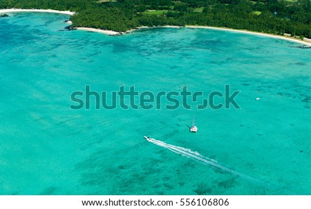 Aerial picture of the east coast of Mauritius Island. Beautiful lagoon of Mauritius Island shot from above. Boat para sailing in turquoise lagoon, recreational kiting activity