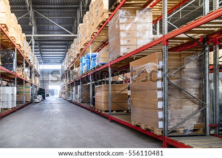 Large hangar warehouse industrial and logistics companies. Boxes and containers with goods placed on high shelves. Royalty-Free Stock Photo #556110481