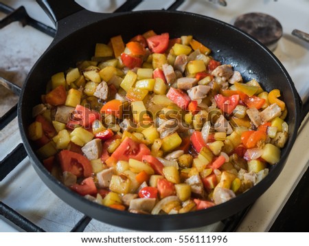 Picture of the frying colourful meal in the pan close up. Background of the colourful frying meal pattern close up. Black frying pan on a white gas stove.