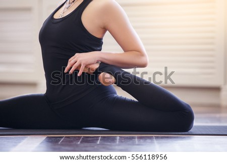 Young asian woman doing yoga pose and asana. Fitness girl enjoying yoga indoors in sport clothes, working out in gym class