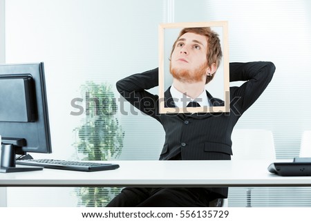 office worker with his arms relaxed and a picture frame with a photo of another face with a dreaming expression