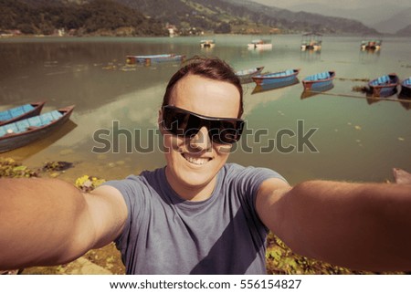 Happy brunette taking a selfie by lakeshore.