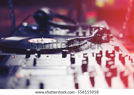 Dj turntable vinyl records player.Professional disc jockey audio equipment to play music.Sound mixer controller on stage in nightclub.Red light leak effect.Vintage djs setup for musical set in club Royalty-Free Stock Photo #556155058