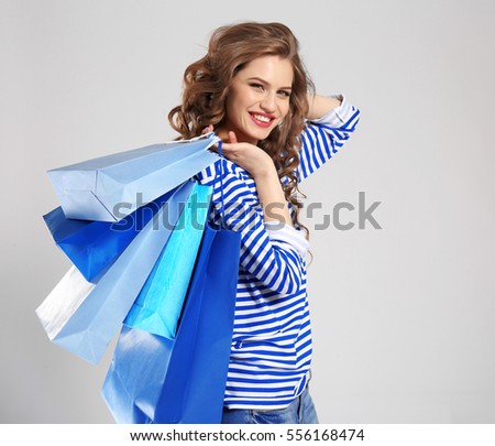 Woman with blue shopping bags on light background