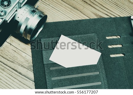 Business travel concept image, top view name card on personal planner book, vintage camera and wooden floor background