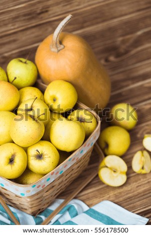 Basket with apples and pumpkins on wooden background