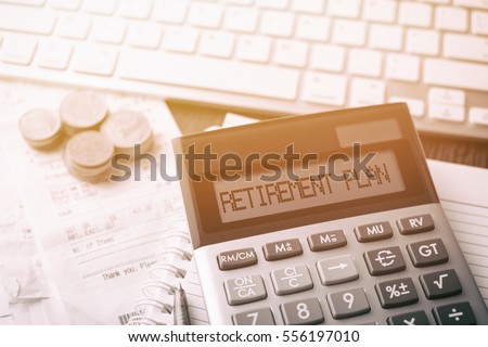 Calculator with text Retirement Plan. Calculator, currency, book, bills and computer keyboard on wooden table. Business, finance, banking conceptual.  Royalty-Free Stock Photo #556197010