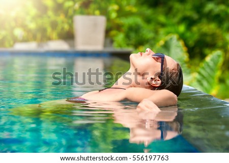 Close up view of an attractive young woman relaxing on a spa's swimming pool.
Travel, happiness emotion, summer holiday concept.