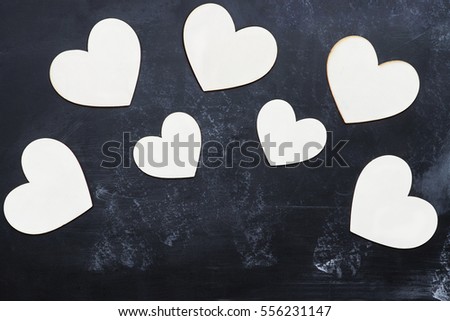 Top view of wooden cut out Valentine's Day hearts over a rustic blackboard with room for copy space.