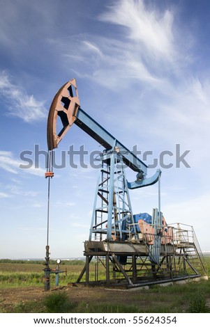 Oil pump jack on a green field