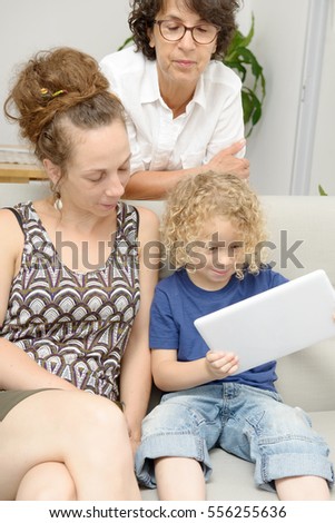 a child and his mother and his grandmother play with tablet