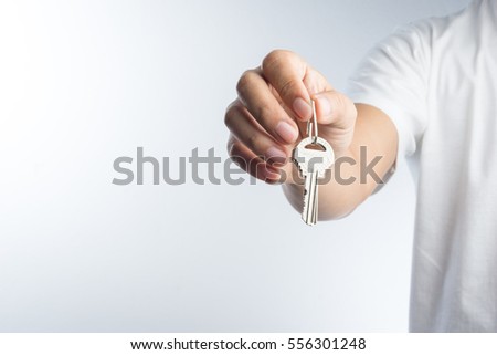 Hand giving keys on white background Royalty-Free Stock Photo #556301248