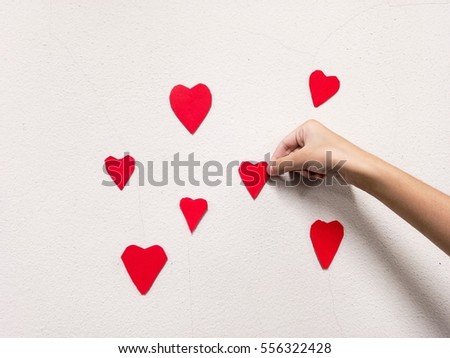 little girl hand stick Red heart shaped on white wall background. Symbol of love on the wall.home decor for valentines day and lovely special occasions to beloved copy space