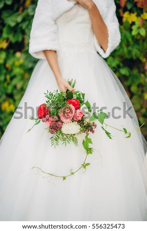 Young pretty woman in white wedding dress posing outdoor with bouquet in early autumn