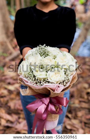 Beautiful woman holding rose bouquet white against autumn background. Valentine day celebration concept