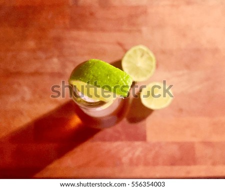 Close up top view of wedge of lime in a fresh cool bottle of non alcoholic beer on a wooden table with two slices of lime. Concept of refreshment
