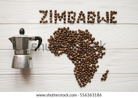 Map of the Africa made of roasted coffee beans laying on white wooden textured background with coffee maker and space for text