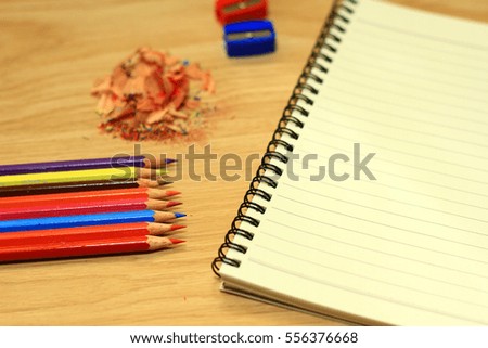 Sharpening a color pencil sharpener and the note book On the wooden floor.