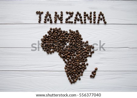 Map of the Africa made of roasted coffee beans laying on white wooden textured background with  space for text